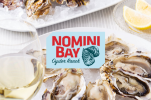 Nomini Bay Oyster Roast logo displayed over fresh oysters and lemon slices